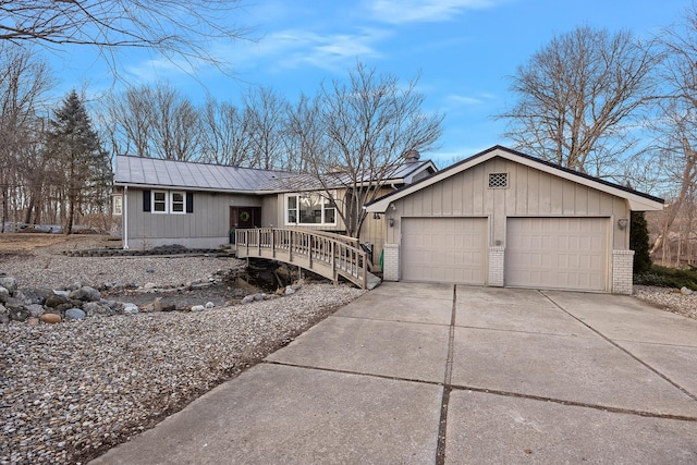 ranch-style home with driveway, a garage, metal roof, and brick siding