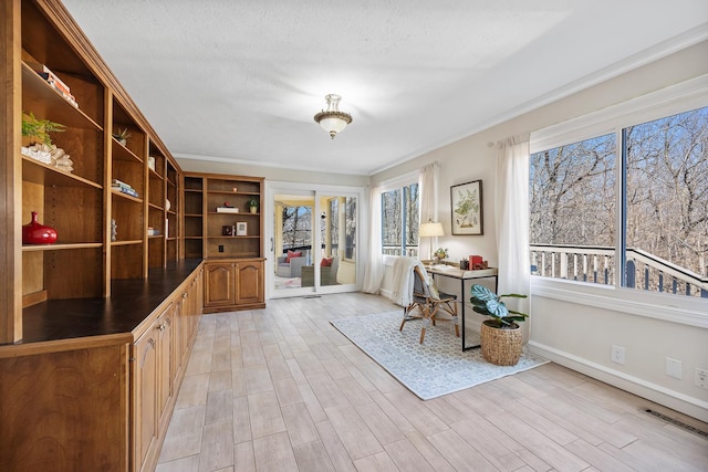 unfurnished office with crown molding, visible vents, light wood-style floors, a textured ceiling, and baseboards