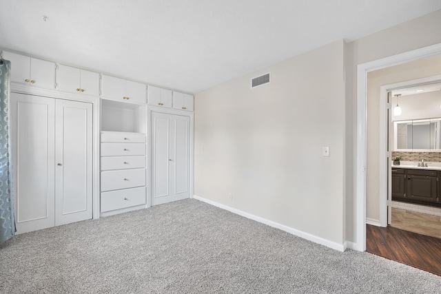 unfurnished bedroom with visible vents, dark carpet, and baseboards