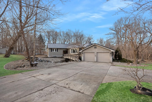 view of front of property featuring driveway, a garage, metal roof, and a front yard