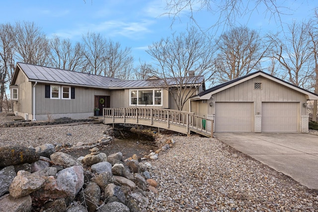 view of front of house with driveway, metal roof, an attached garage, a deck, and brick siding