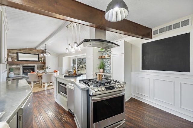 kitchen featuring stainless steel appliances, wall chimney range hood, dark wood-style flooring, and a stone fireplace