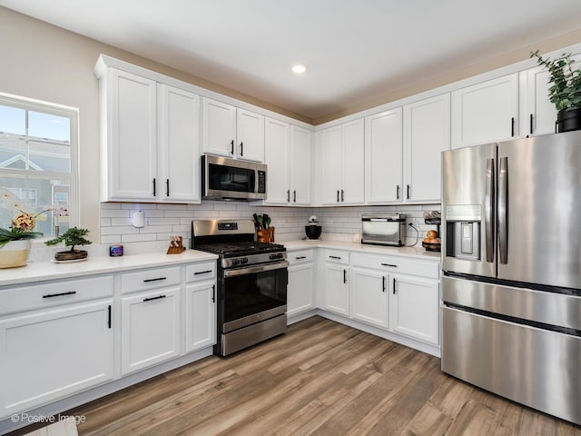 kitchen featuring white cabinets, decorative backsplash, light hardwood / wood-style floors, and appliances with stainless steel finishes