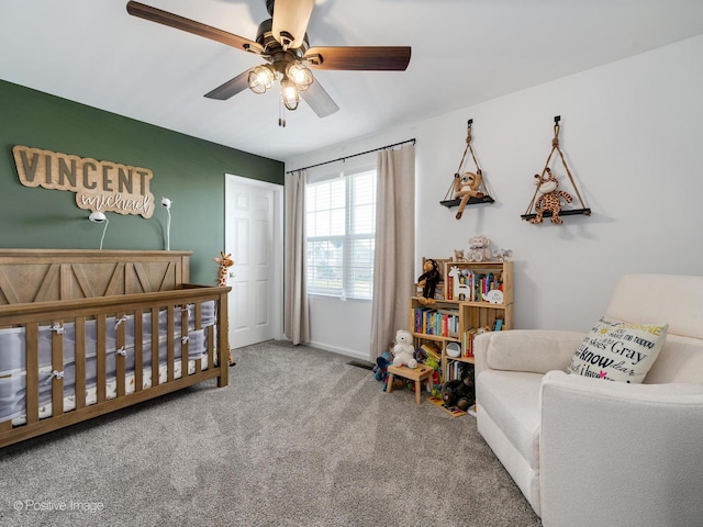 carpeted bedroom featuring ceiling fan and a nursery area