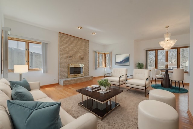 living room with light wood-type flooring, a fireplace, and a chandelier