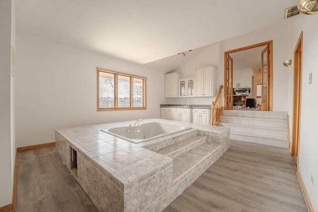 bathroom with hardwood / wood-style flooring, vanity, a bathing tub, and lofted ceiling