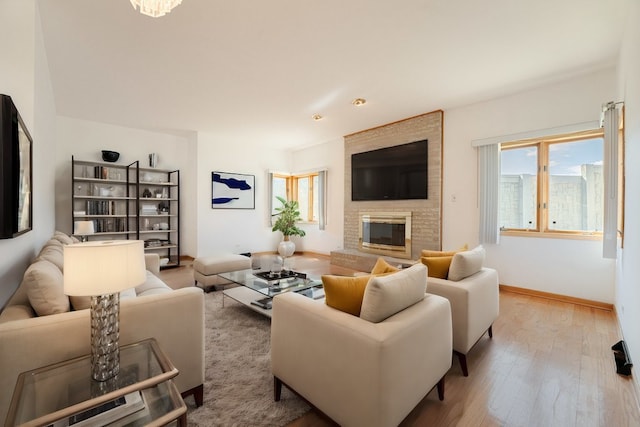 living area featuring a brick fireplace, baseboards, and wood finished floors