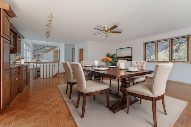 dining room featuring light parquet flooring, a healthy amount of sunlight, and ceiling fan with notable chandelier