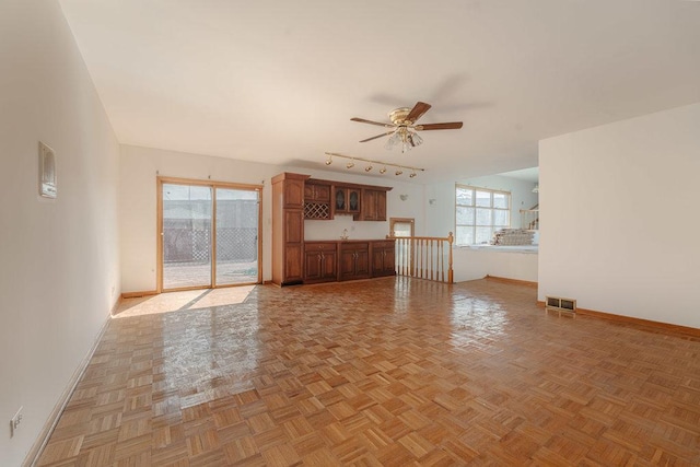 unfurnished living room featuring a ceiling fan, track lighting, visible vents, and baseboards