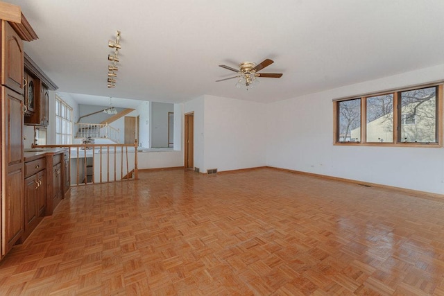 empty room with track lighting, visible vents, baseboards, and ceiling fan with notable chandelier