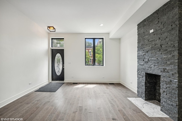 entrance foyer featuring wood-type flooring and a stone fireplace