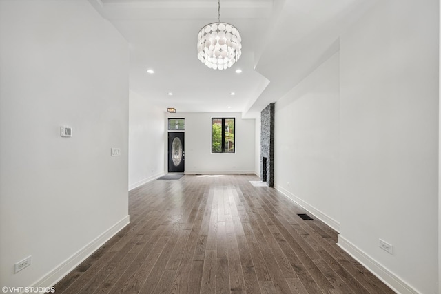 corridor with dark hardwood / wood-style floors and an inviting chandelier