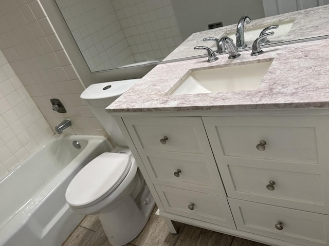 full bathroom featuring hardwood / wood-style floors, vanity, toilet, and tiled shower / bath