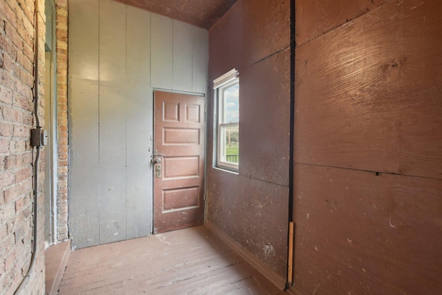 corridor with brick wall and light wood-type flooring