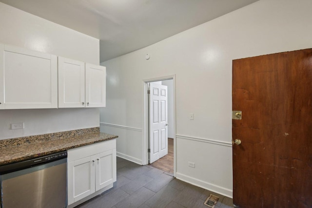 kitchen with dark stone countertops, dark wood-type flooring, white cabinets, and stainless steel dishwasher