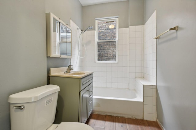 full bathroom with hardwood / wood-style floors, vanity, toilet, and tiled shower / bath combo