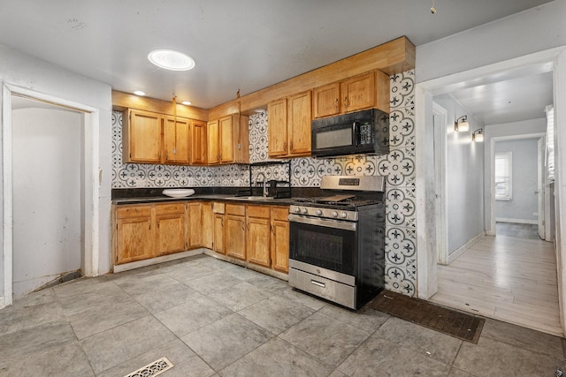 kitchen featuring decorative backsplash, stainless steel range with gas cooktop, and sink