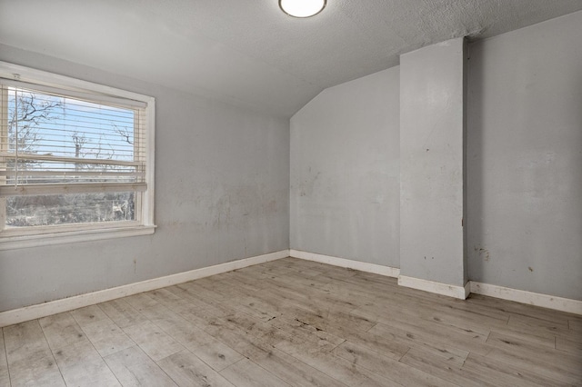 bonus room featuring light hardwood / wood-style flooring, a textured ceiling, and lofted ceiling