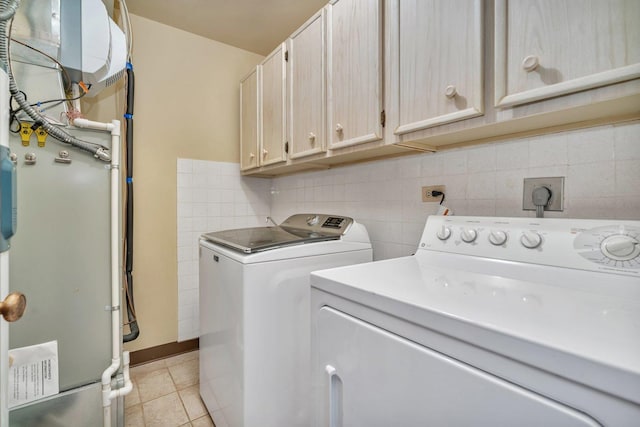 clothes washing area with cabinets, light tile patterned flooring, and washing machine and dryer