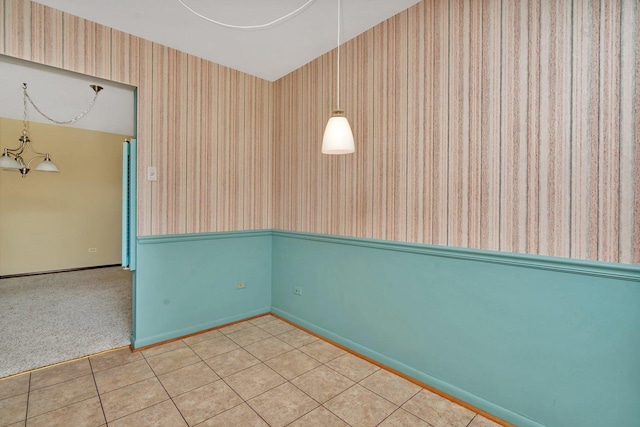 spare room featuring tile patterned flooring and a chandelier