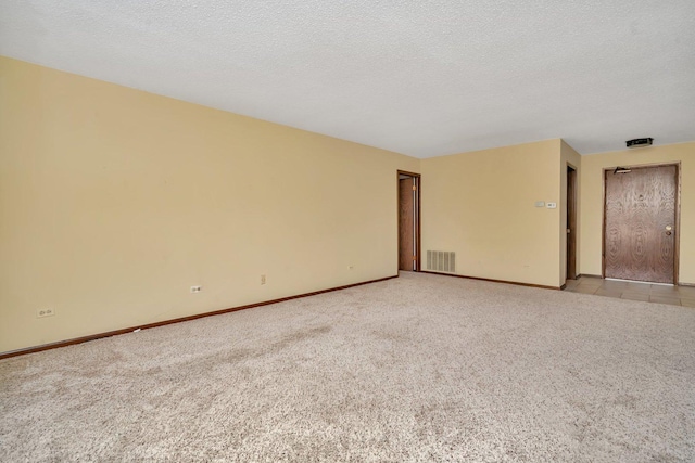 spare room featuring a textured ceiling and light colored carpet