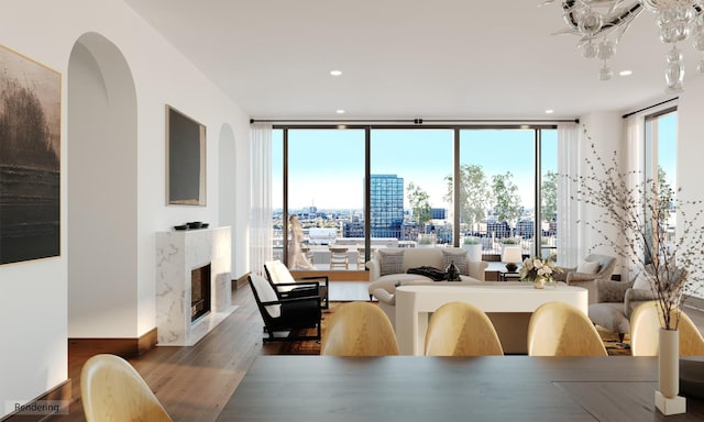 dining space with hardwood / wood-style floors, a high end fireplace, and a wall of windows