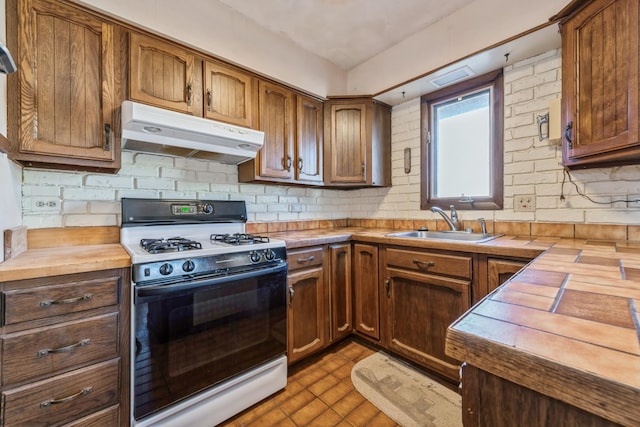 kitchen with white range with gas stovetop, butcher block countertops, tasteful backsplash, and sink