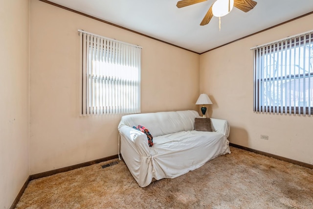 living area with a wealth of natural light, ceiling fan, light carpet, and ornamental molding