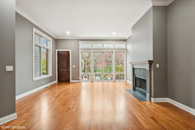 unfurnished living room featuring plenty of natural light, light wood-type flooring, and ornamental molding