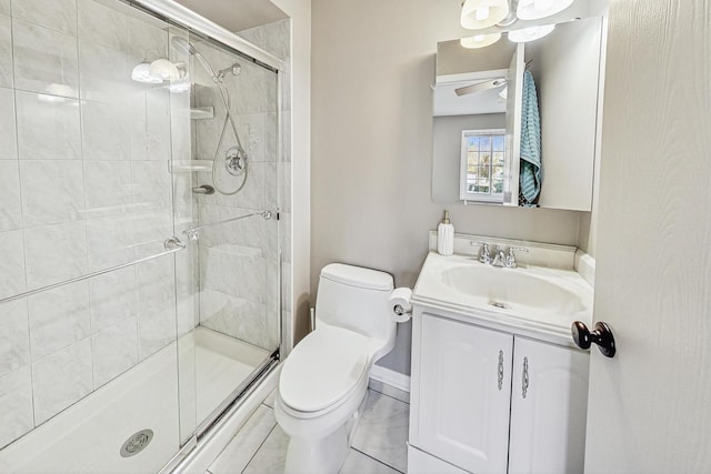 bathroom featuring vanity, toilet, a shower with door, and ceiling fan