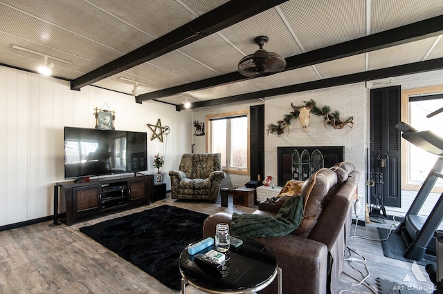 living room featuring a large fireplace, beamed ceiling, and hardwood / wood-style flooring