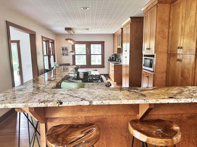 kitchen with hanging light fixtures, stainless steel appliances, a breakfast bar area, and dark wood-type flooring