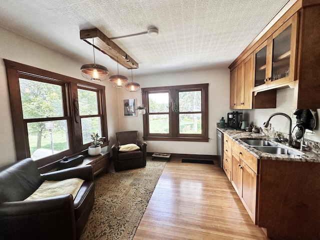 kitchen featuring plenty of natural light, stone countertops, sink, and light hardwood / wood-style flooring