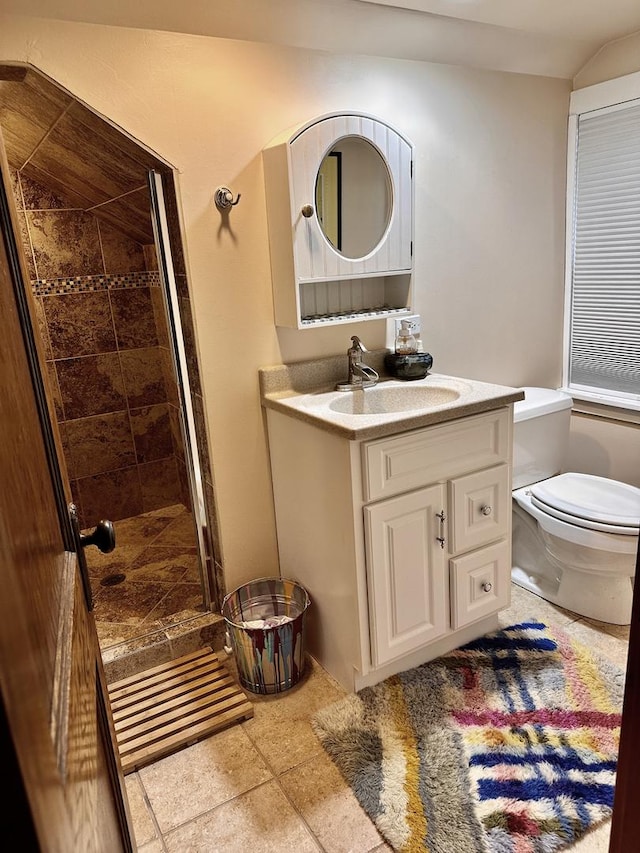 bathroom featuring vanity, toilet, and tiled shower