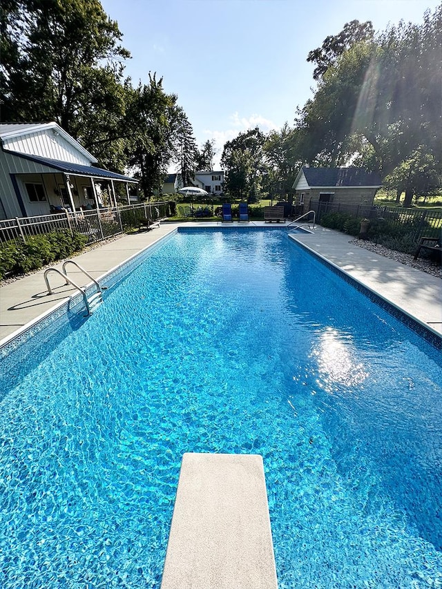 view of swimming pool with a diving board