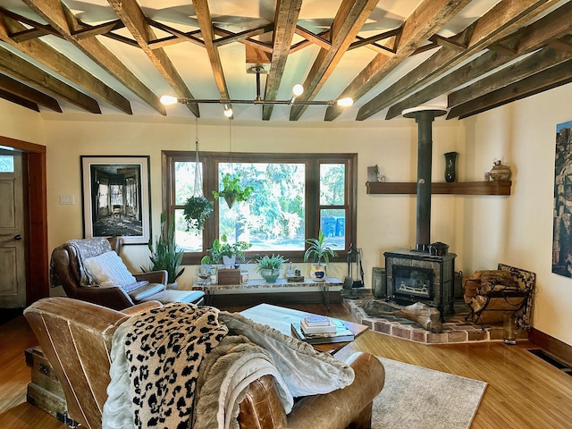 living room with beam ceiling, hardwood / wood-style flooring, and a wood stove