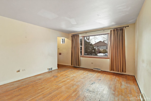 unfurnished room featuring visible vents, hardwood / wood-style flooring, and baseboards