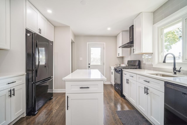 kitchen featuring black appliances, sink, wall chimney exhaust hood, a wealth of natural light, and white cabinetry