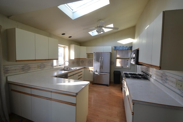 kitchen featuring appliances with stainless steel finishes, light countertops, white cabinets, and a sink