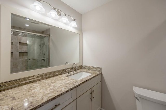 bathroom featuring vanity, backsplash, toilet, and a shower with door