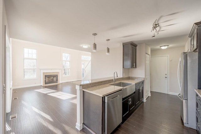 kitchen featuring stainless steel appliances, hanging light fixtures, dark wood-type flooring, and sink