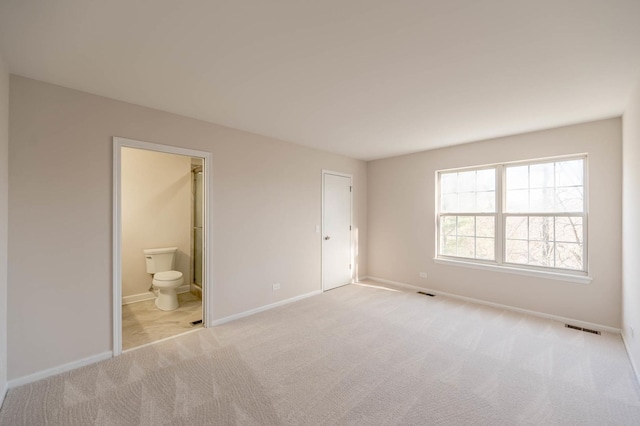 unfurnished bedroom featuring light carpet, connected bathroom, and a closet