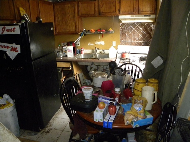 kitchen featuring black fridge, light tile patterned floors, and sink