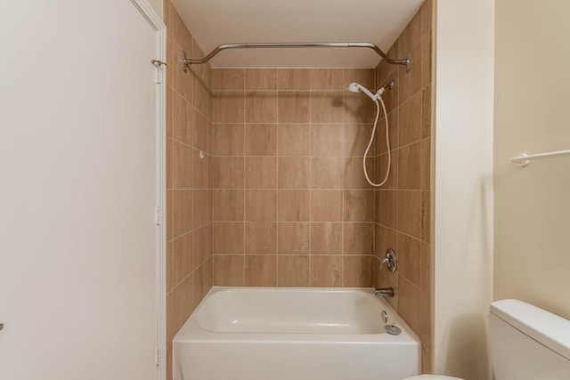 bathroom with toilet and tiled shower / bath