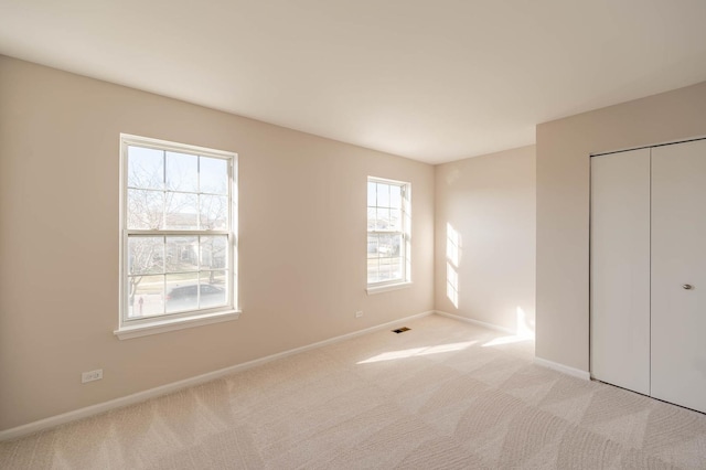 unfurnished bedroom with a closet, light carpet, and multiple windows