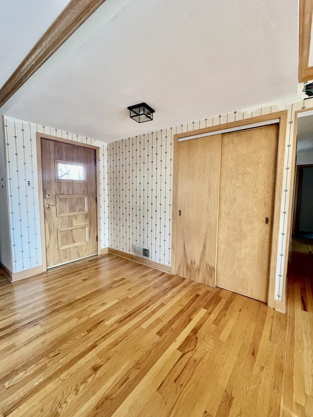 unfurnished bedroom featuring a closet, beamed ceiling, and hardwood / wood-style flooring