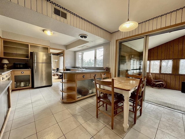 dining area featuring lofted ceiling, wood walls, and light tile patterned floors