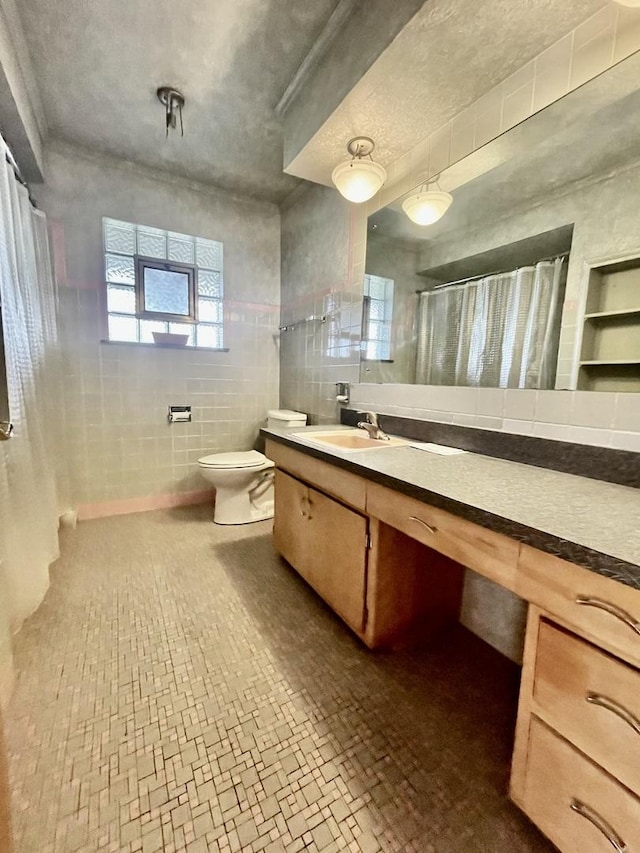 bathroom with a shower with shower curtain, a textured ceiling, vanity, tile walls, and toilet