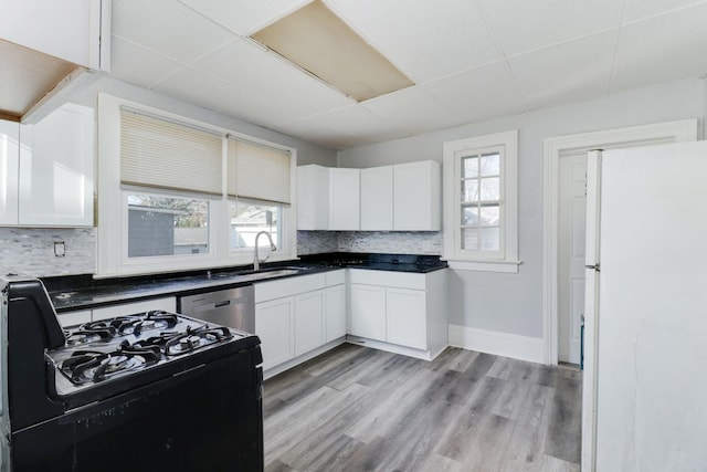 kitchen featuring light wood-type flooring, backsplash, gas stove, white refrigerator, and white cabinets