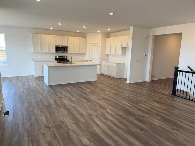 kitchen with stainless steel appliances, dark hardwood / wood-style flooring, an island with sink, and white cabinets